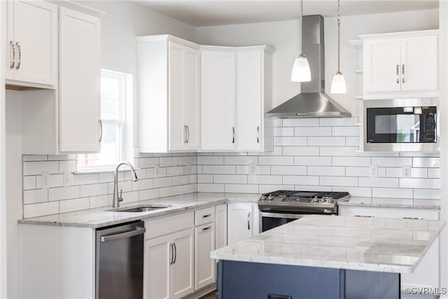 kitchen with decorative backsplash, stainless steel appliances, wall chimney range hood, white cabinetry, and a sink