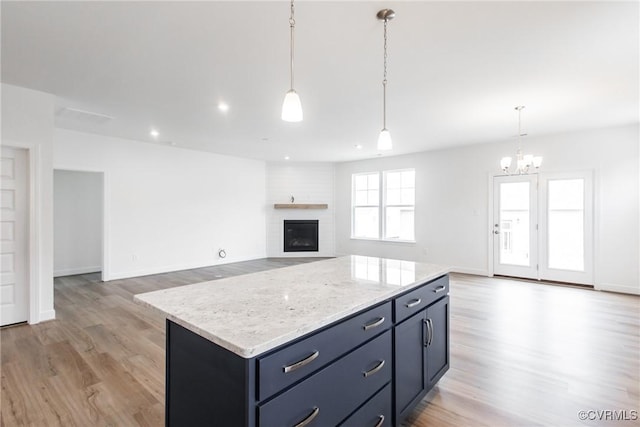 kitchen featuring light wood-type flooring, a center island, a fireplace, and hanging light fixtures