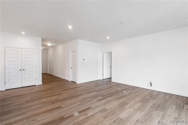 unfurnished room with baseboards, light wood finished floors, and recessed lighting