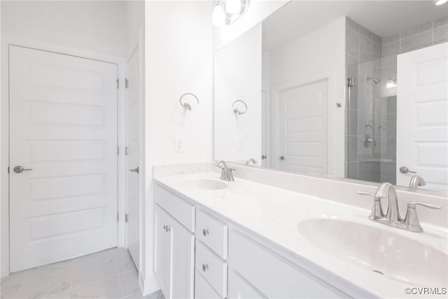 bathroom with double vanity, marble finish floor, a shower stall, and a sink