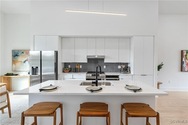 kitchen featuring a breakfast bar area, white cabinetry, sink, and stainless steel appliances