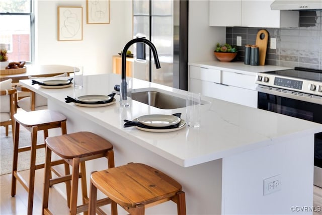 kitchen with a kitchen breakfast bar, decorative backsplash, white cabinets, and stainless steel appliances