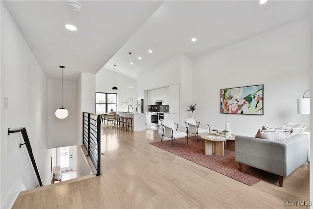 living room featuring high vaulted ceiling and light wood-type flooring