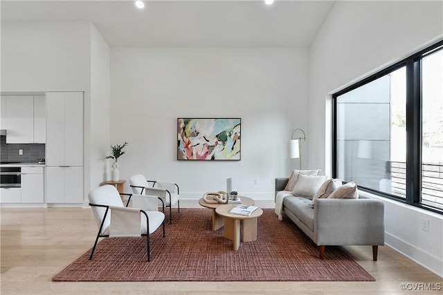 living room with a towering ceiling and light wood-type flooring