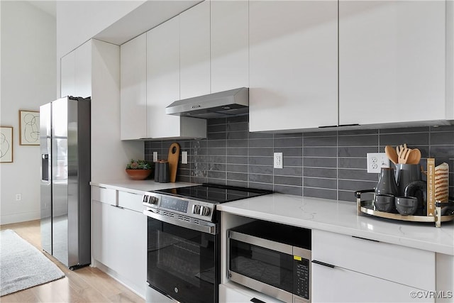 kitchen with decorative backsplash, white cabinetry, stainless steel appliances, and ventilation hood