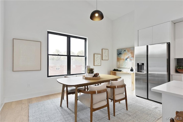 dining area with light hardwood / wood-style flooring and a high ceiling