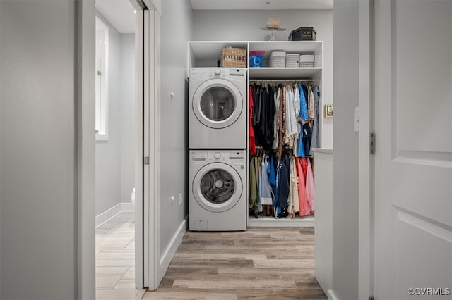 laundry room with stacked washing maching and dryer and light hardwood / wood-style flooring