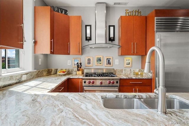 kitchen with light stone counters, ventilation hood, and high quality appliances