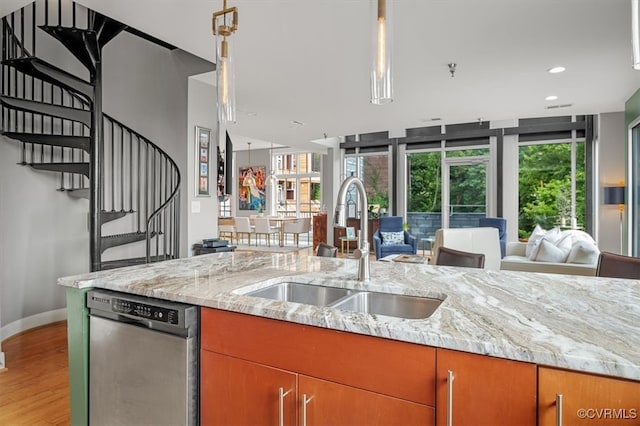 kitchen with light hardwood / wood-style floors, light stone counters, sink, and stainless steel dishwasher