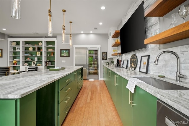 kitchen with green cabinetry, light hardwood / wood-style flooring, light stone countertops, sink, and tasteful backsplash