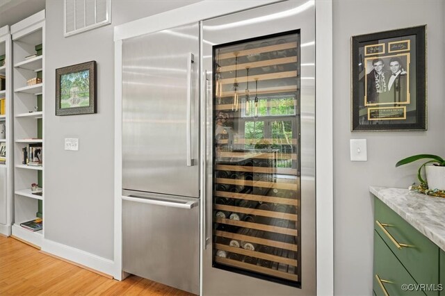 interior space featuring light wood-type flooring, stainless steel built in fridge, and green cabinets