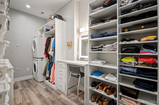 spacious closet featuring stacked washer and clothes dryer and light hardwood / wood-style floors