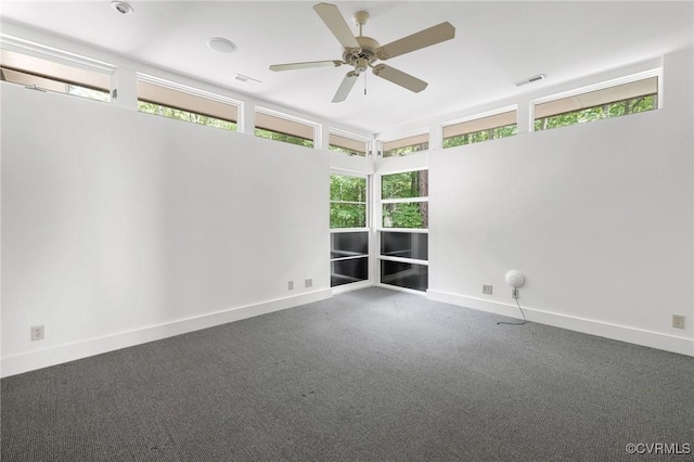 carpeted spare room featuring visible vents, baseboards, and ceiling fan