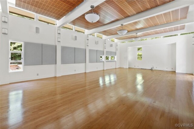 interior space with light hardwood / wood-style flooring, a high ceiling, and beamed ceiling