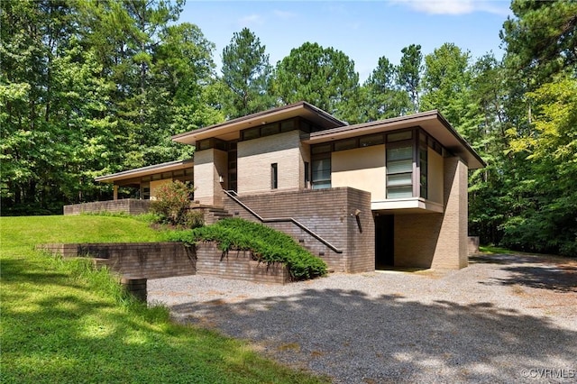 view of front of house with a front lawn, brick siding, and stairs