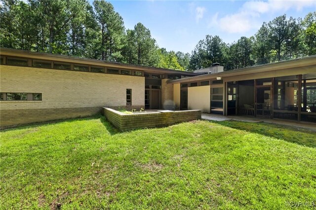 rear view of property with a lawn and a patio