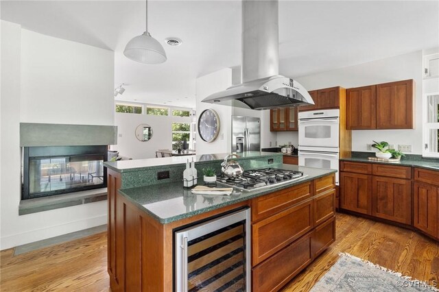 kitchen with wine cooler, island range hood, light hardwood / wood-style flooring, appliances with stainless steel finishes, and a center island