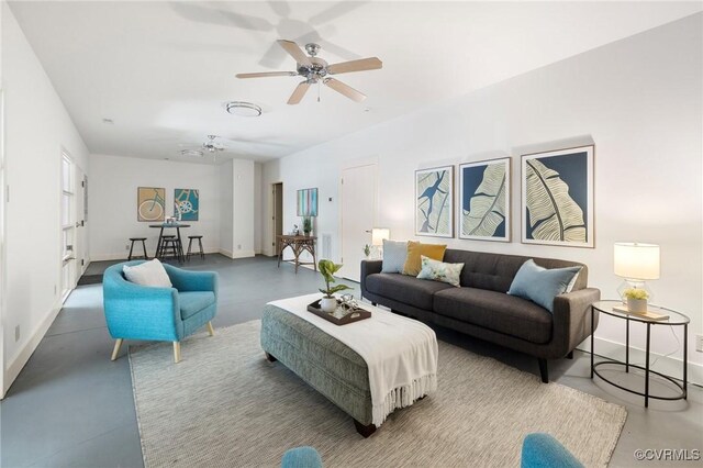 living room with ceiling fan and concrete flooring