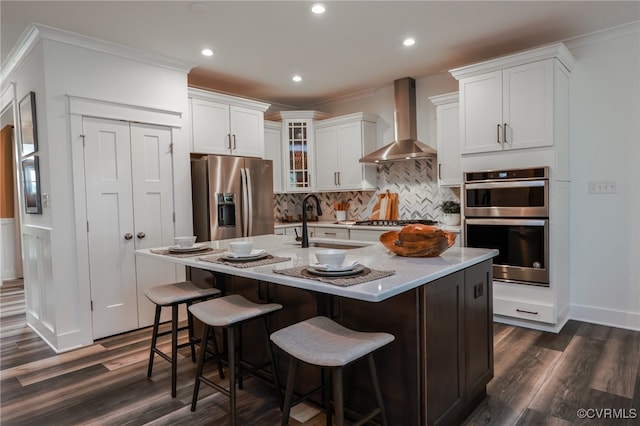 kitchen featuring appliances with stainless steel finishes, dark hardwood / wood-style flooring, wall chimney exhaust hood, and backsplash