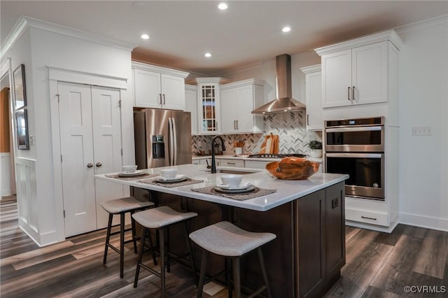 kitchen featuring crown molding, stainless steel appliances, dark wood-type flooring, and wall chimney range hood