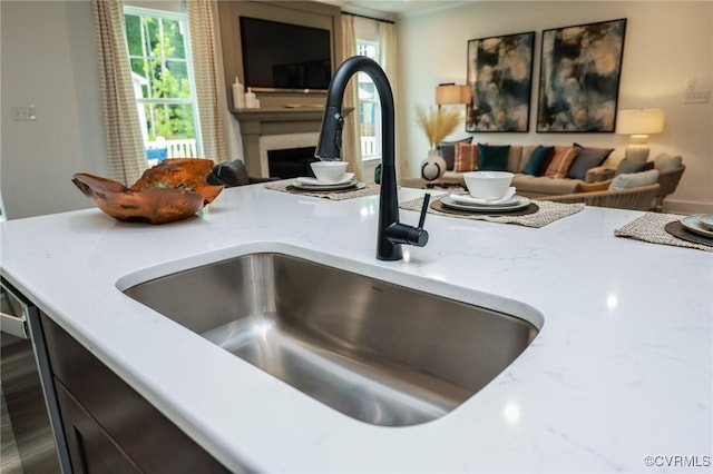 interior details with a fireplace, light stone countertops, and a sink