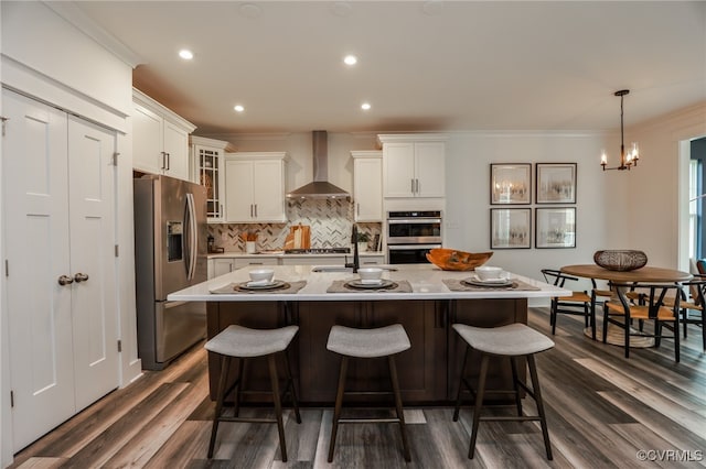 kitchen with wall chimney range hood, white cabinetry, appliances with stainless steel finishes, and dark wood-type flooring