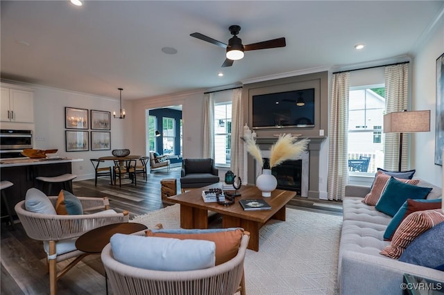 living room featuring wood finished floors, a large fireplace, a healthy amount of sunlight, and ornamental molding