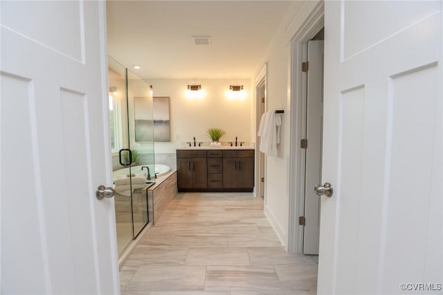 full bath with double vanity, visible vents, a garden tub, and a sink