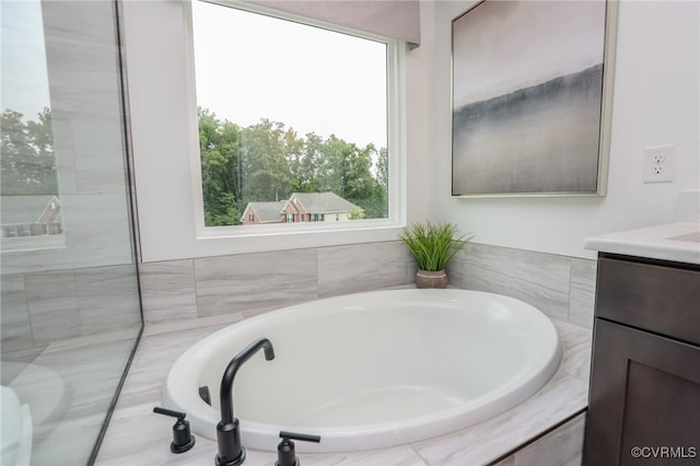 bathroom featuring a relaxing tiled tub and vanity