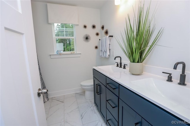 full bathroom with baseboards, toilet, double vanity, marble finish floor, and a sink