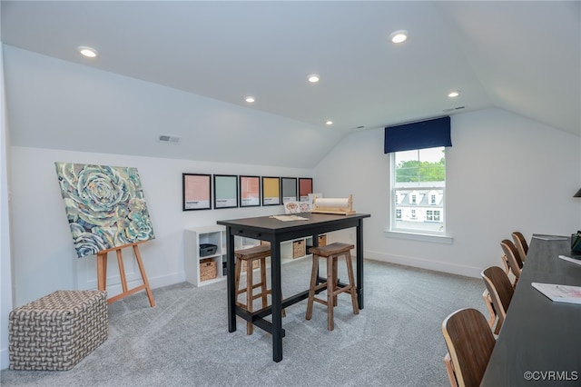 carpeted dining area with vaulted ceiling