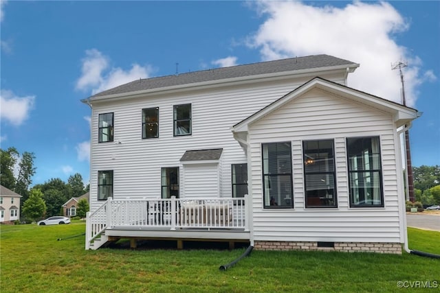 rear view of house featuring a deck and a lawn