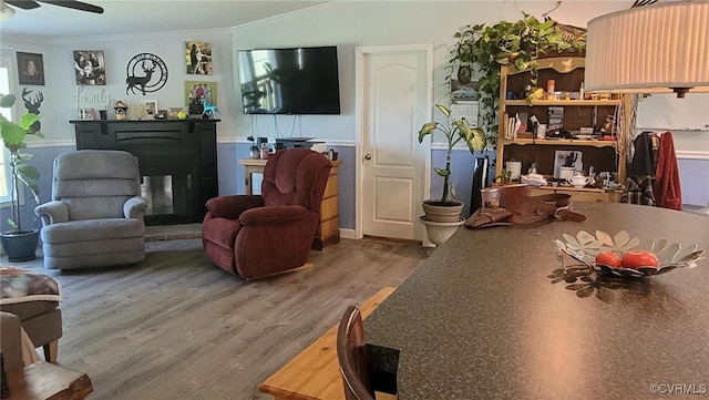 living room with ornamental molding, wood-type flooring, and ceiling fan