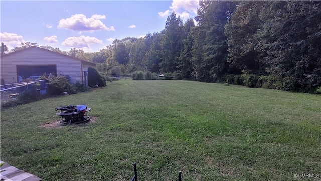 view of yard with a garage, an outbuilding, and an outdoor fire pit