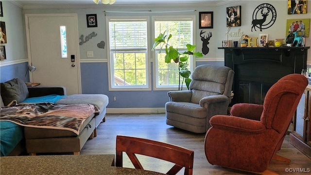 living room with ornamental molding, a fireplace, baseboards, and wood finished floors