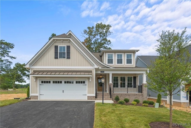 craftsman house featuring a standing seam roof, a porch, a front lawn, a garage, and aphalt driveway