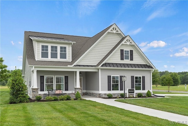 craftsman-style home with a standing seam roof, a front lawn, and stone siding