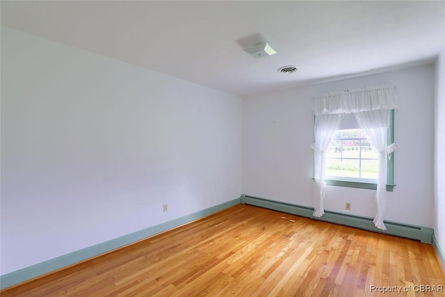 empty room with light hardwood / wood-style floors and baseboard heating