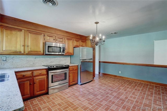 kitchen with tasteful backsplash, light stone counters, decorative light fixtures, an inviting chandelier, and stainless steel appliances