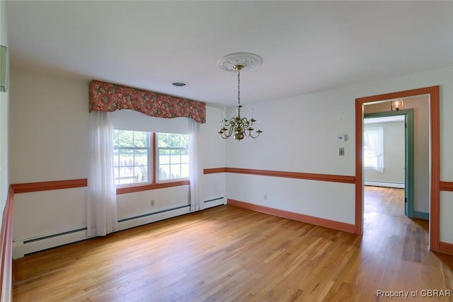 empty room featuring a notable chandelier, light hardwood / wood-style floors, and a baseboard heating unit