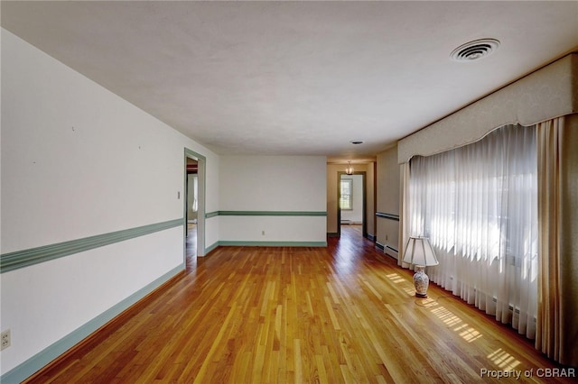 empty room featuring light wood-type flooring and baseboard heating