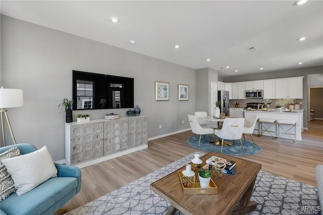 living room featuring light wood-style flooring, baseboards, and recessed lighting