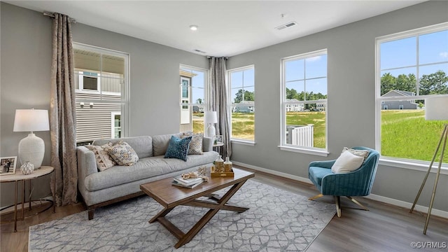 living room with baseboards, wood finished floors, visible vents, and a healthy amount of sunlight