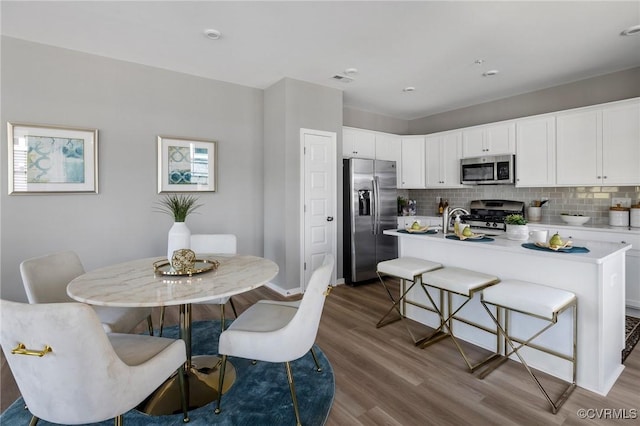 kitchen with dark wood-style flooring, light countertops, decorative backsplash, appliances with stainless steel finishes, and white cabinets