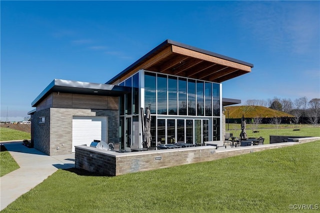 rear view of house featuring a patio, a lawn, and an attached garage