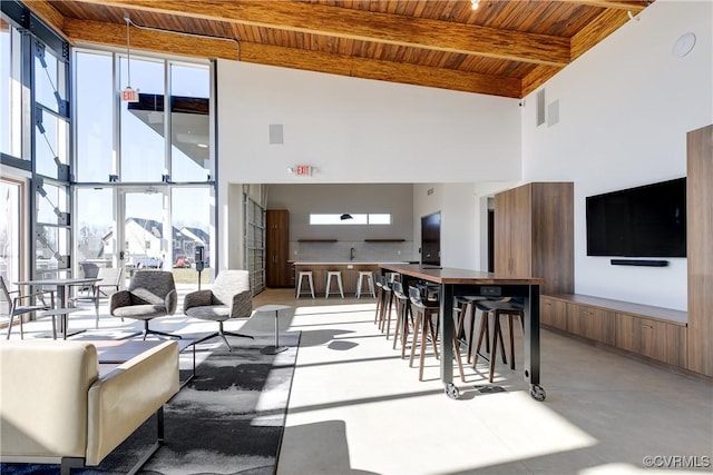 living area with floor to ceiling windows, a towering ceiling, wood ceiling, concrete flooring, and beamed ceiling