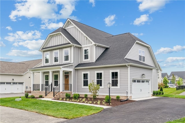 view of front of property featuring roof with shingles, a porch, a front lawn, aphalt driveway, and board and batten siding