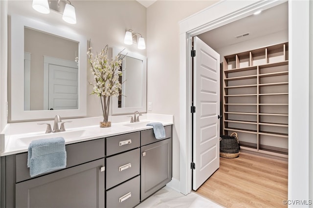 full bath featuring a sink, visible vents, wood finished floors, and double vanity