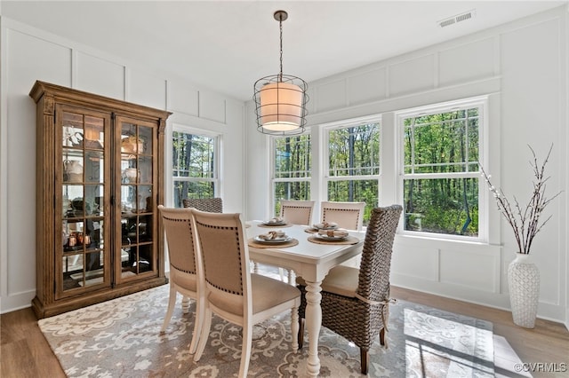 dining room with a decorative wall, visible vents, and light wood finished floors