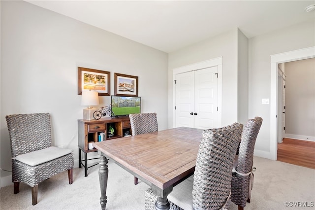 dining room featuring light colored carpet and baseboards